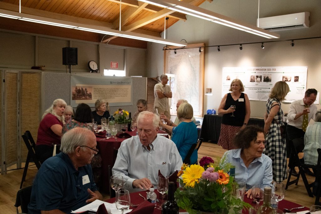 A wide view of guests seated at round tables in the Heritage Center hall.