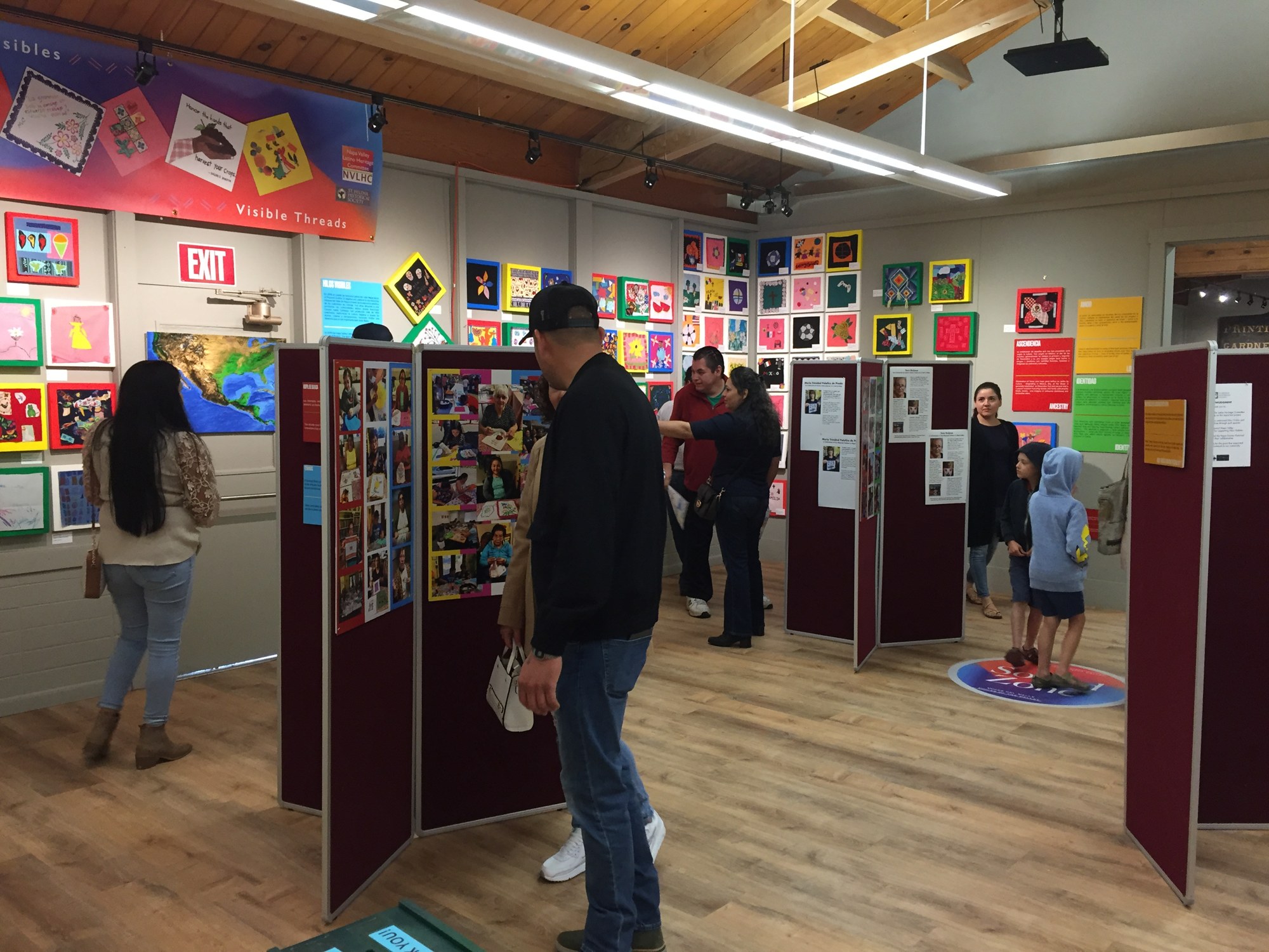 Visitors view quilt squares and photo panels at the Hilos Visibles (Visible Threads) exhibit, 2022
